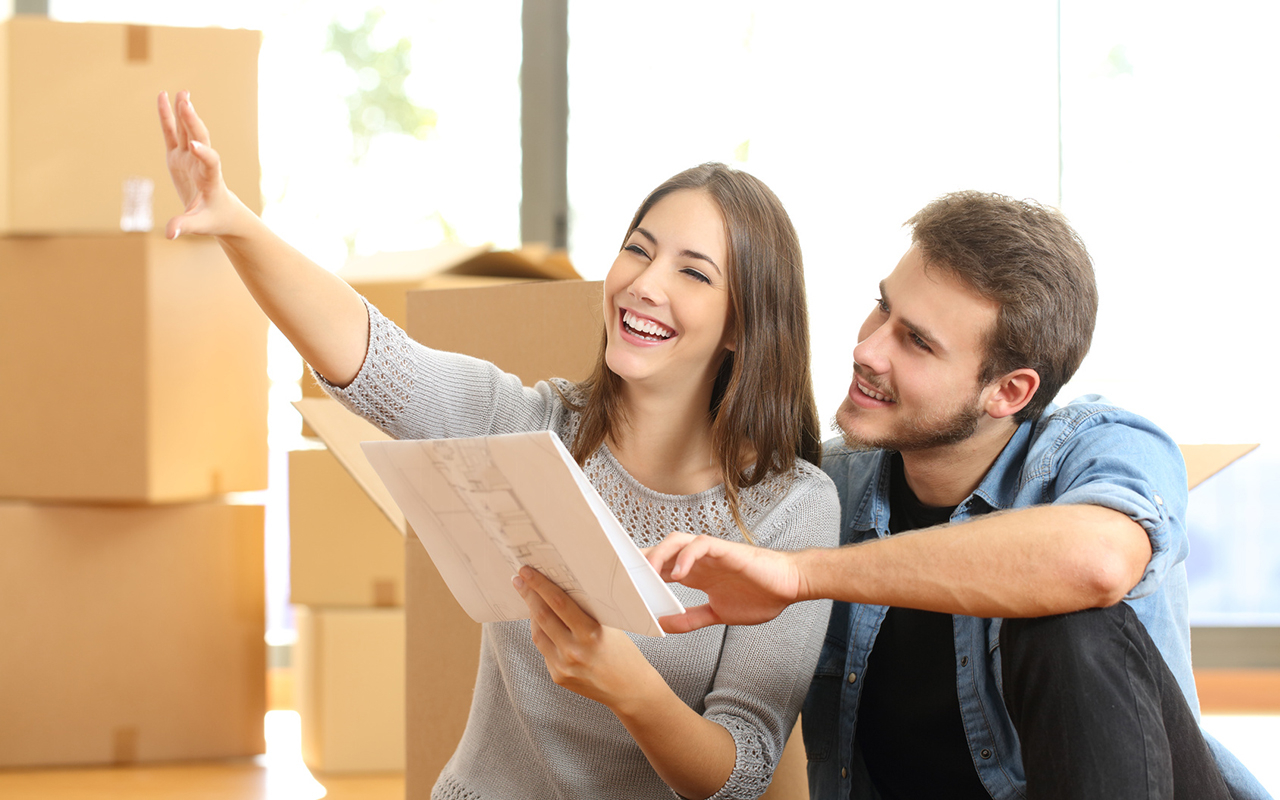 Happy couple planning decoration when moving into their new home sitting on the floor